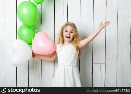 Cheerful little blonde girl with balloons on white wood background. Cheerful little blonde girl with balloons on white wood background.