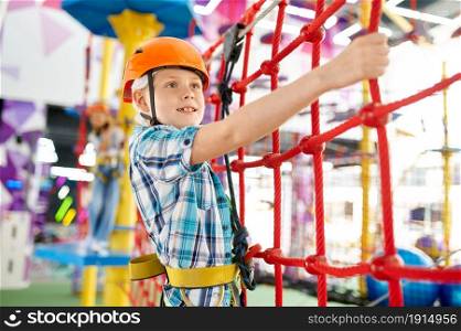Cheerful little boy on zip line in entertainment center. Children having fun in climbing area, kids spend the weekend on playground, happy childhood. Little boy on zip line in entertainment center