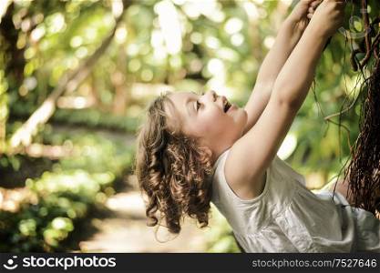 Cheerful, little daughter climbing on a palm tree
