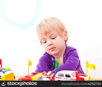 Cheerful little girl playing with toys isolated on white background