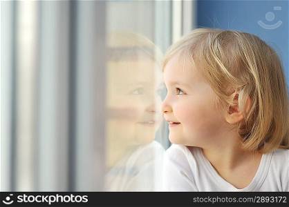 cheerful little girl sits at window portrait
