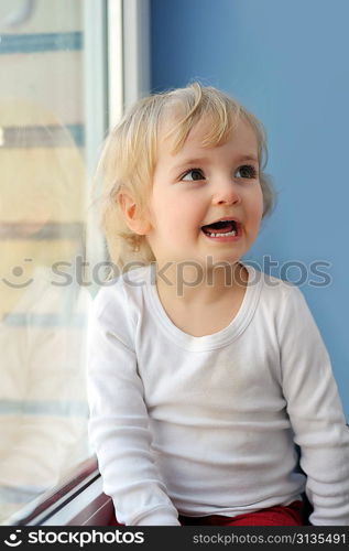 cheerful little girl sits at window portrait