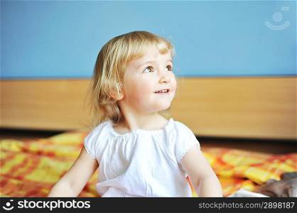 cheerful little girl sits on bed of parents