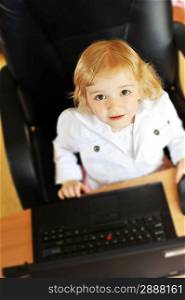 cheerful little girl with laptop sitting at table