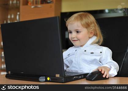 cheerful little girl with laptop sitting at table