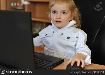 cheerful little girl with laptop sitting at table