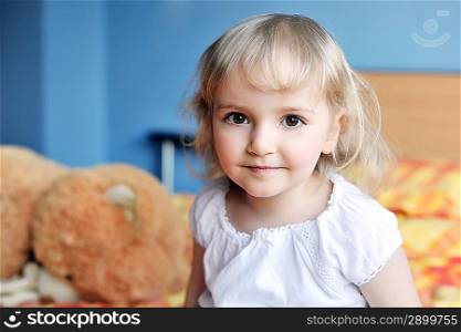 cheerful little girl with soft toy sits on bed of parents
