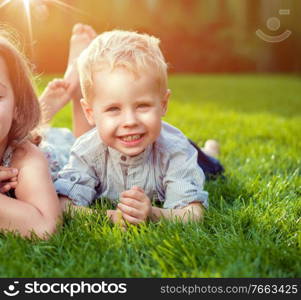 Cheerful little siblings relaxing on a fresh lawn