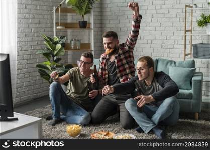 cheerful male friends watching sports tv having pizza