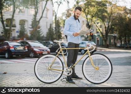 cheerful man reading newspaper near bike