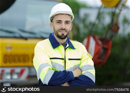 cheerful man with arms crossed standing next to lorry