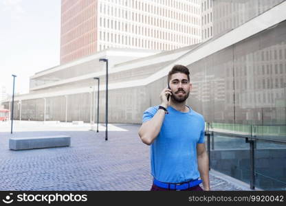 Cheerful modern businessman speaking by phone and smiling while walking outdoors