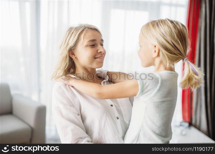 Cheerful mother and child hugs at home. Parent feeling, togetherness, happy family