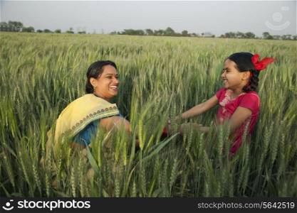Cheerful mother and daughter playing in the wheat field