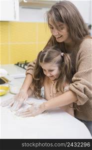 cheerful mother daughter putting flour table