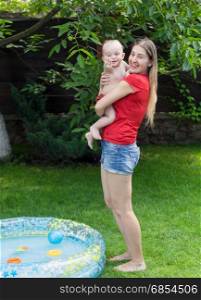 Cheerful mother embracing her baby boy after swimming in pool