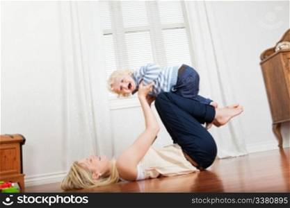 Cheerful mother playing with her cute loving baby boy at home
