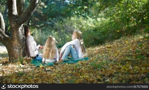 Cheerful mother with two daughters spending time together enjoying sunny autumn day