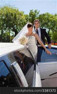 Cheerful newly wed couple getting in the car