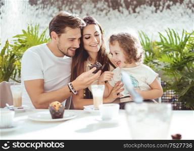 Cheerful parents feeding their beloved daughter