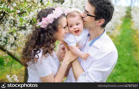 Cheerful parents kissing their beloved baby