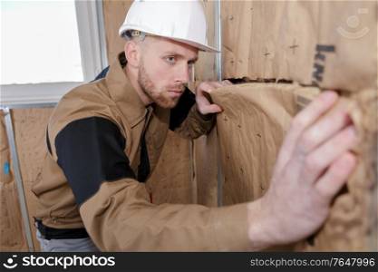 cheerful plasterer worker at a indoors wall insulation works