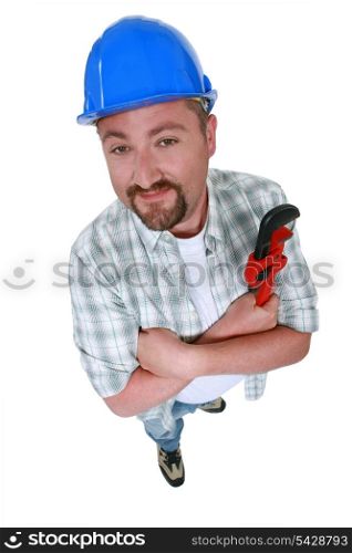 Cheerful plumber holding adjustable wrench