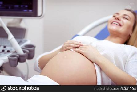 Cheerful pregnant woman on ultrasound, joyful future mother checking health of her baby in the clinic, happy preparation for parenthood