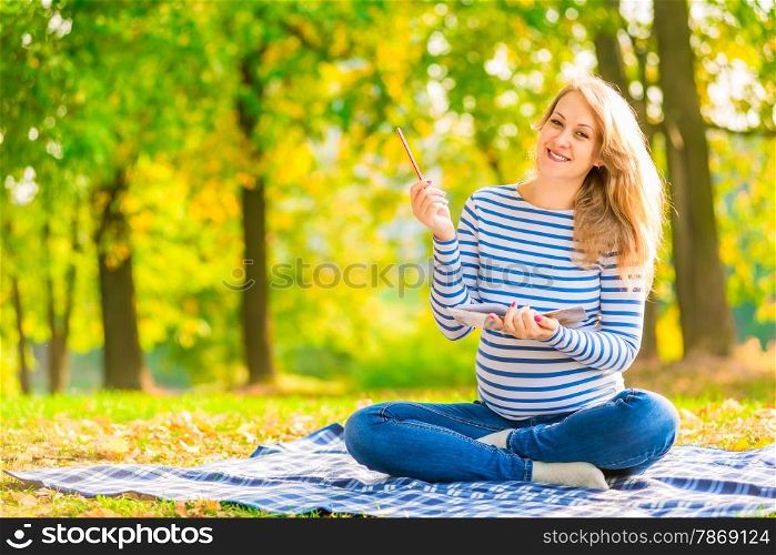 cheerful pregnant woman with a notebook and pencil