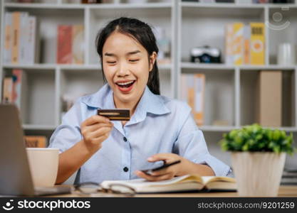 Cheerful pretty young woman using mobile phone shopping online and payment by credit bank card