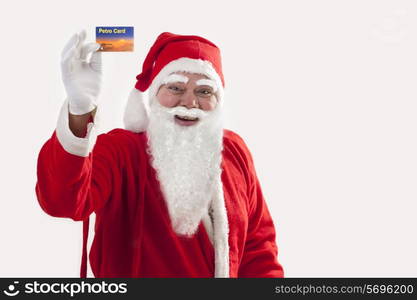 Cheerful Santa Claus showing petro card over colored background