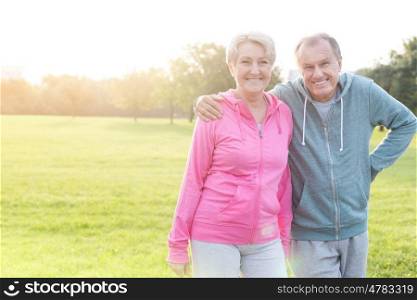 Cheerful senior man and woman in sportswear standing at park