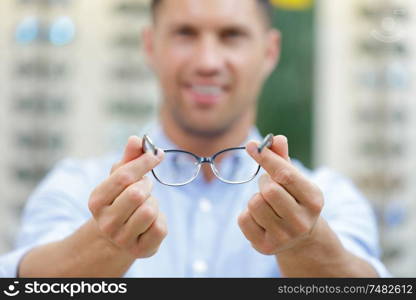 cheerful smart man trying glasses on