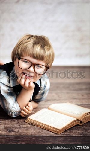 Cheerful smiling little boy reading a book