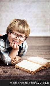 Cheerful smiling little boy reading a book