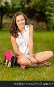 Cheerful student girl with pink briefcase sitting on grass summer