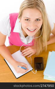 Cheerful student woman write homework, listen to music