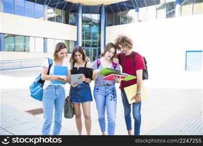 cheerful students with tablet textbooks near university building