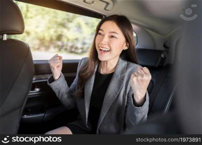 cheerful successed young business woman sitting at the back seat of car