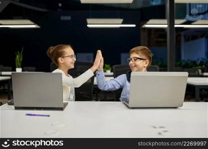 Cheerful successful kids coworker colleague giving high five celebrate project victory in office. Cheerful successful children coworkers colleagues giving highfive