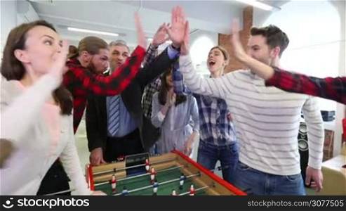 Cheerful team of people doing high five after playing table football