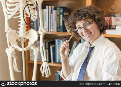 cheerful teen girl sitting near skeleton model