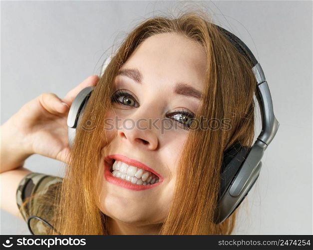 Cheerful teenage woman listening to music through big headphones having fun. Bizarre crazy close up.. Teen women wearing headphones