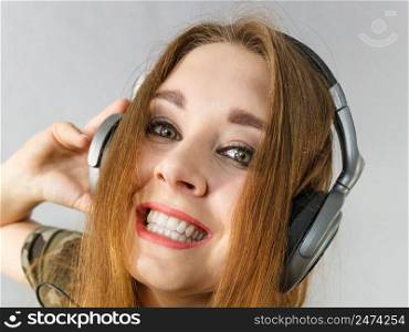 Cheerful teenage woman listening to music through big headphones having fun. Bizarre crazy close up.. Teen women wearing headphones