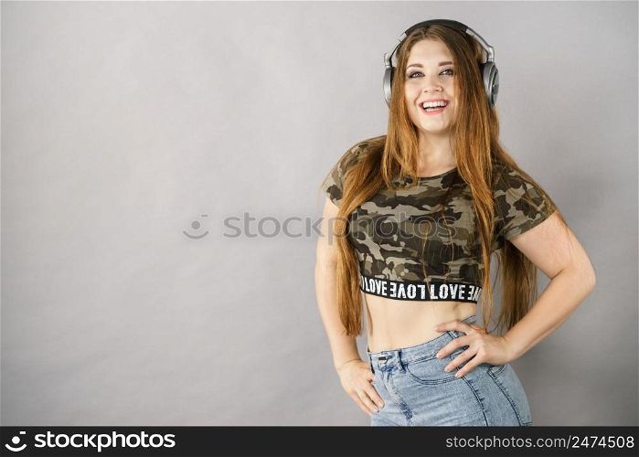Cheerful teenage woman listening to music through big headphones having fun. Crazy girl. Teen women wearing headphones