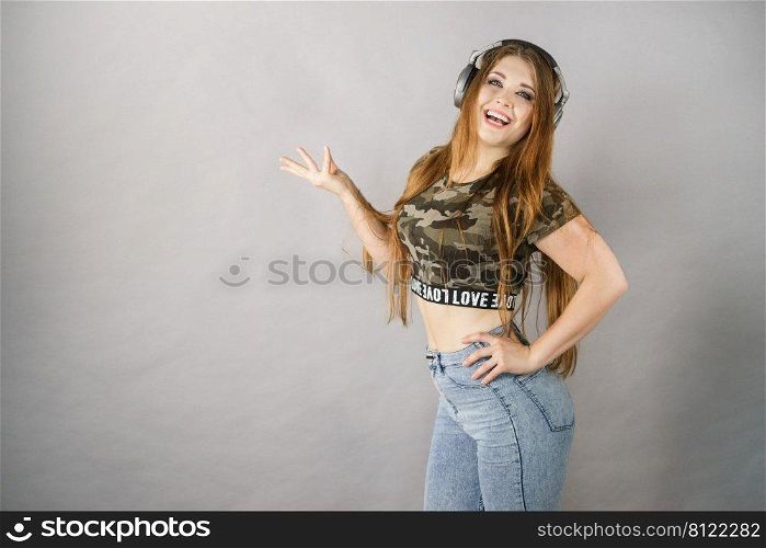 Cheerful teenage woman listening to music through big headphones having fun. Crazy girl. Teen women wearing headphones