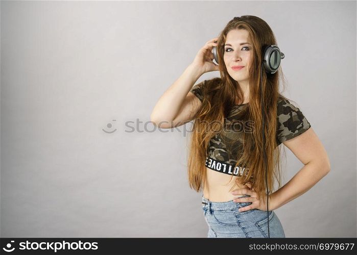 Cheerful teenage woman listening to music through big headphones having fun.. Teen women wearing headphones