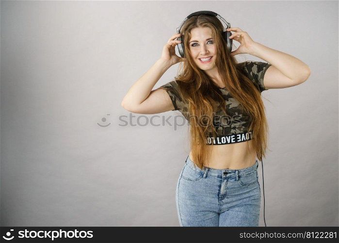 Cheerful teenage woman listening to music through big headphones having fun.. Teen women wearing headphones