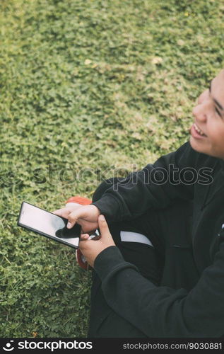 cheerful teenager of Latino descent smiles as he looks at his smartphone screen. The boy&rsquo;s relaxed posture and cheerful expression convey a sense of contentment. Background blurred to focus attention on the boy and his phone.. Smiling latino teenager looking at his smartphone screen