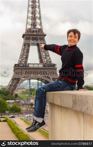 Cheerful teenager shows the Eiffel tower (La Tour Eiffel) in Paris, France